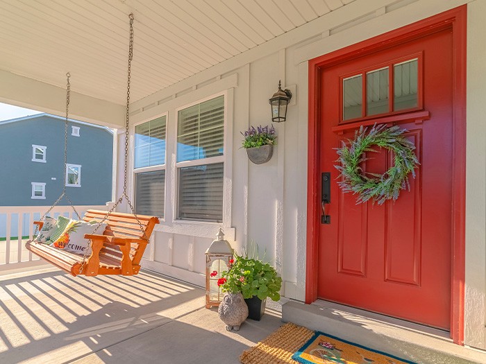 Porche avant d’une maison avec une porte en bois rouge.
