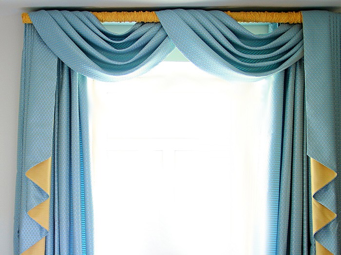 Fenêtre ornée d’une guirlande turquoise négligemment enroulée autour d’une tringle.